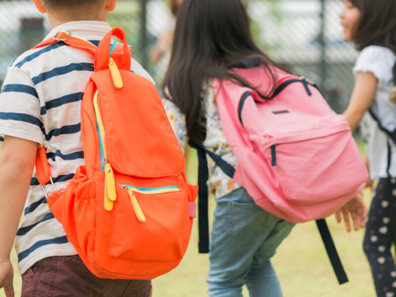 tres alumnos escuela primaria van mano muchacho muchacha bolsos escuela detras parte posterior comienzo clases dia calido otono vuelta escuela pequenos estudiantes primer grado