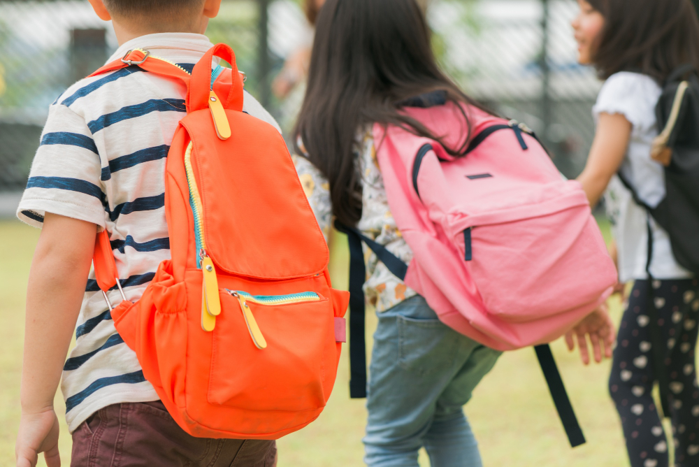 tres alumnos escuela primaria van mano muchacho muchacha bolsos escuela detras parte posterior comienzo clases dia calido otono vuelta escuela pequenos estudiantes primer grado